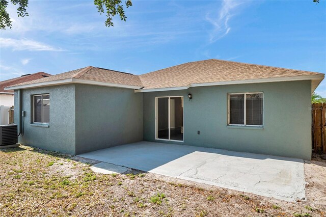 back of house with fence, central AC, stucco siding, a patio, and roof with shingles