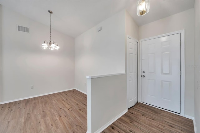 foyer with wood finished floors, a chandelier, lofted ceiling, and baseboards