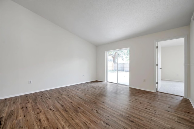 spare room with wood finished floors, baseboards, and lofted ceiling