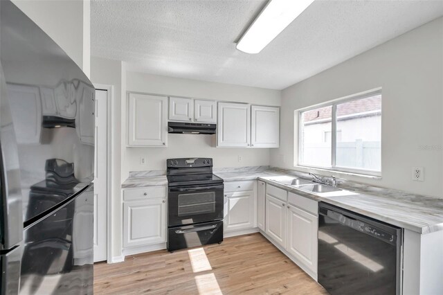 kitchen with black appliances, under cabinet range hood, a sink, white cabinetry, and a textured ceiling