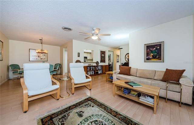 368 Perth Ct Unit 368, Dunedin, FL 34698 - living room with light wood-style flooring, a ceiling fan, a chandelier, baseboards, and a textured ceiling