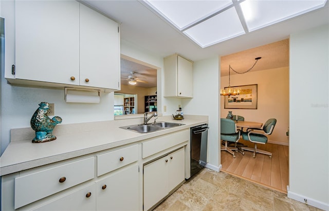 368 Perth Ct Unit 368, Dunedin, FL 34698 - kitchen featuring black dishwasher, a sink, light countertops, baseboards, and white cabinetry