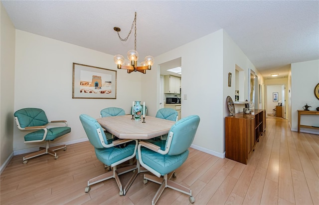 368 Perth Ct Unit 368, Dunedin, FL 34698 - dining room featuring a chandelier, light wood finished floors, baseboards, and a textured ceiling