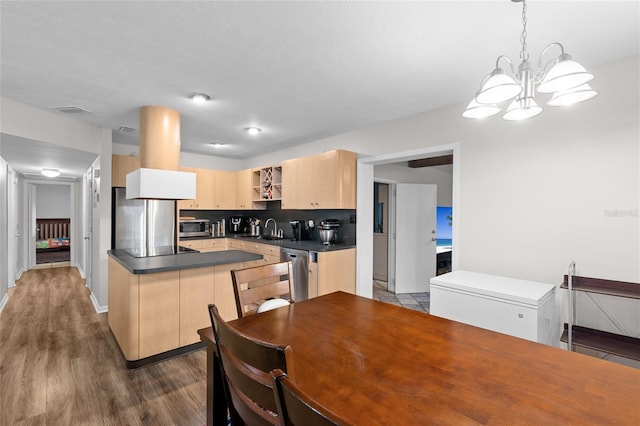8001 N Ola Ave, Tampa, FL 33604 - kitchen featuring appliances with stainless steel finishes, dark countertops, wood finished floors, light brown cabinets, and a chandelier