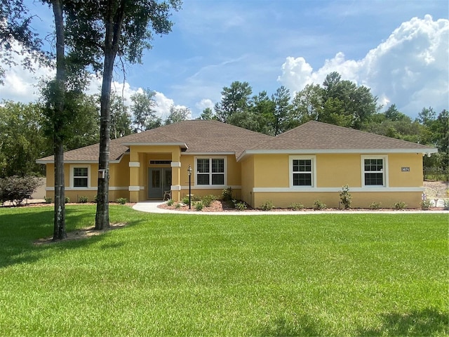 ranch-style home featuring stucco siding, a front lawn, and roof with shingles