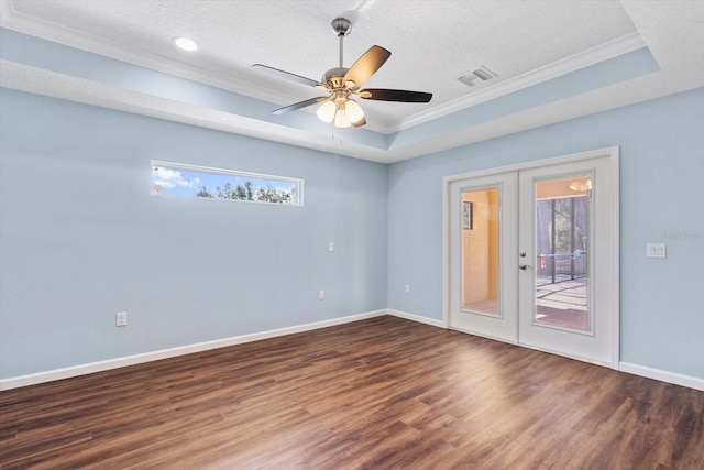 empty room featuring crown molding, french doors, wood finished floors, a raised ceiling, and baseboards