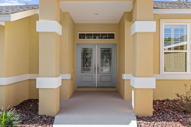 doorway to property with french doors, stucco siding, and a shingled roof