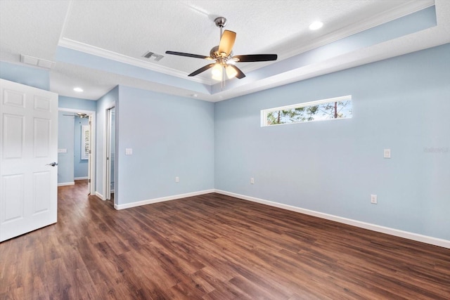 unfurnished bedroom featuring a tray ceiling, baseboards, wood finished floors, ornamental molding, and a textured ceiling