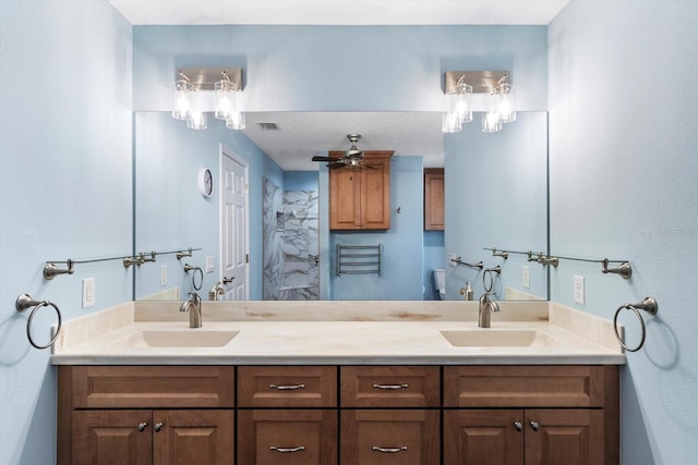 bathroom featuring a ceiling fan, toilet, and double vanity