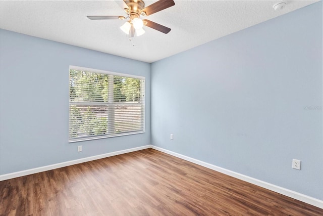 spare room featuring wood finished floors, baseboards, ceiling fan, and a textured ceiling