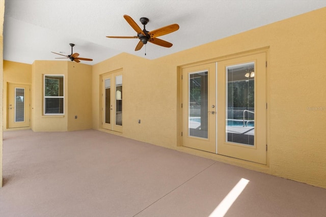 carpeted spare room featuring french doors and a ceiling fan