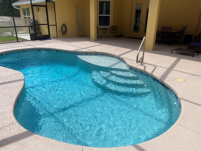 view of swimming pool featuring a patio area and glass enclosure