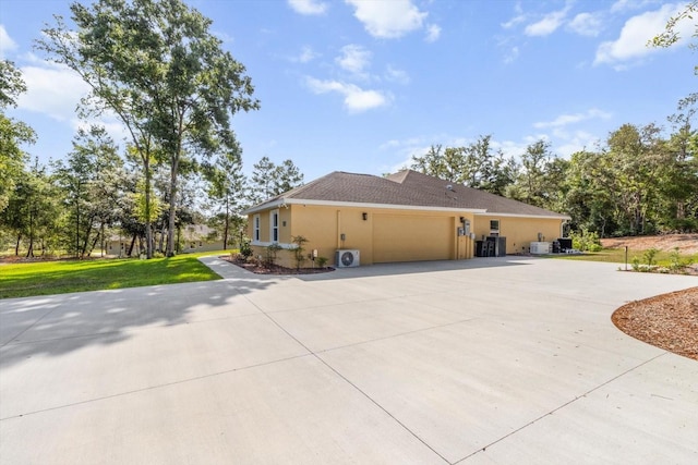 view of home's exterior featuring curved driveway, an attached garage, stucco siding, and a lawn