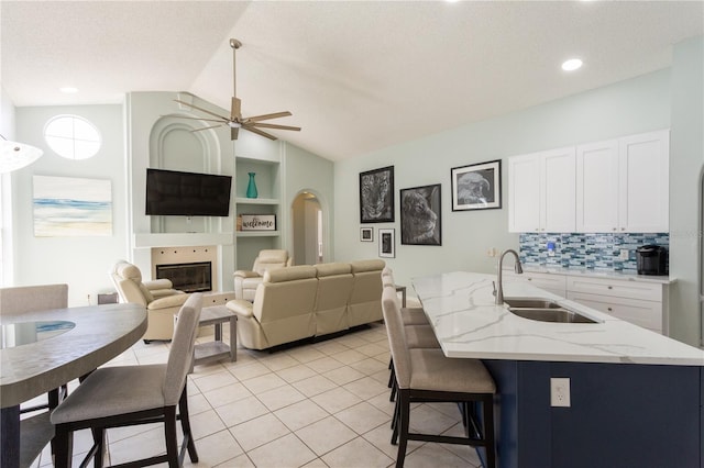 7838 Trail Run Loop, New Port Richey, FL 34653 - kitchen featuring a sink, a ceiling fan, a glass covered fireplace, vaulted ceiling, and light tile patterned floors