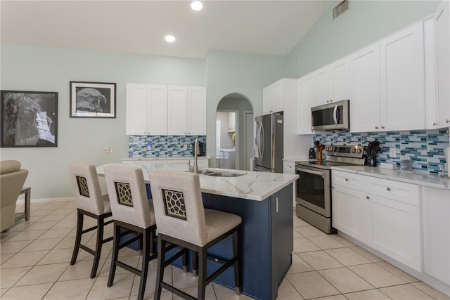7838 Trail Run Loop, New Port Richey, FL 34653 - kitchen featuring appliances with stainless steel finishes, tasteful backsplash, a breakfast bar area, arched walkways, and light tile patterned flooring