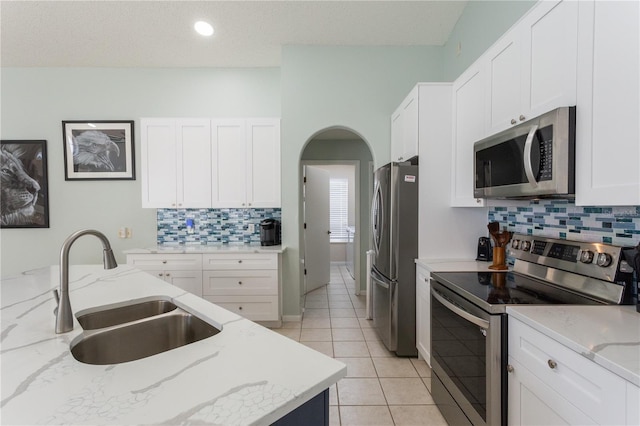 7838 Trail Run Loop, New Port Richey, FL 34653 - kitchen featuring appliances with stainless steel finishes, a sink, tasteful backsplash, white cabinets, and light stone counters