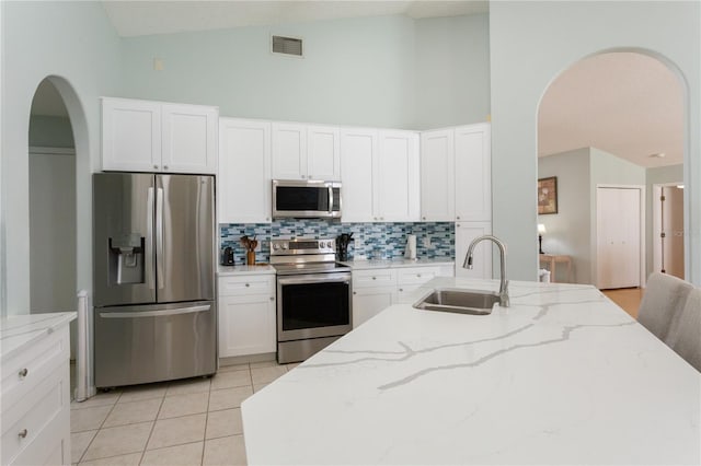 7838 Trail Run Loop, New Port Richey, FL 34653 - kitchen featuring appliances with stainless steel finishes, a sink, arched walkways, tasteful backsplash, and light tile patterned floors