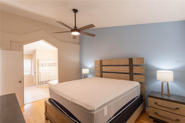 7838 Trail Run Loop, New Port Richey, FL 34653 - bedroom featuring light wood-style flooring, connected bathroom, a textured ceiling, and ceiling fan
