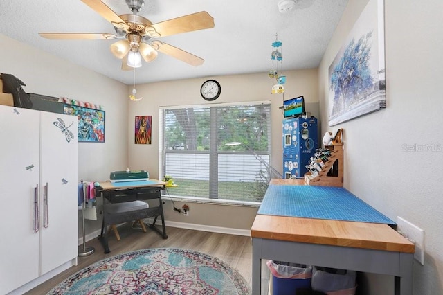 playroom featuring wood finished floors, a ceiling fan, and an office area