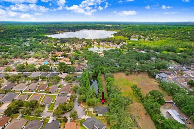 aerial overview of property's location with a nearby body of water, nearby suburban area, and a heavily wooded area