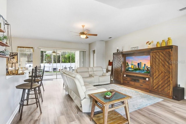 living area featuring a ceiling fan, light wood-style flooring, and baseboards