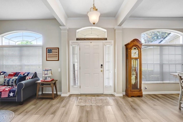 entrance foyer with decorative columns, light wood finished floors, plenty of natural light, crown molding, and beamed ceiling