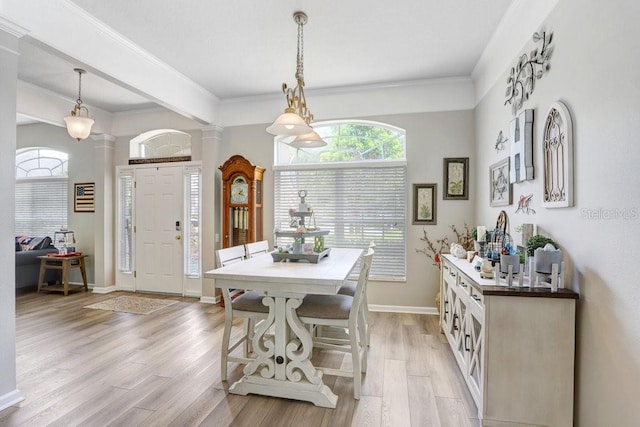 dining area featuring ornate columns, light wood-style floors, baseboards, and crown molding
