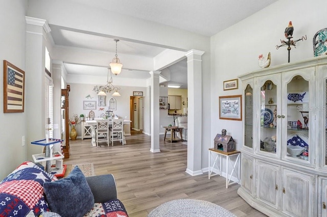 living room featuring decorative columns, light wood finished floors, and baseboards