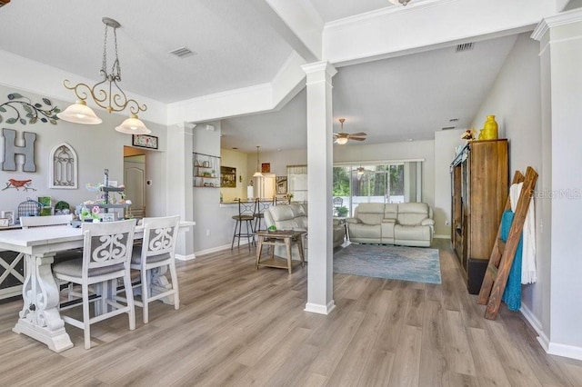 dining space featuring decorative columns, baseboards, light wood-style flooring, ceiling fan, and vaulted ceiling