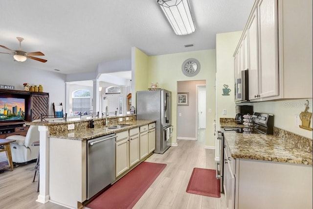 kitchen with stainless steel appliances, light wood-type flooring, a sink, and a peninsula