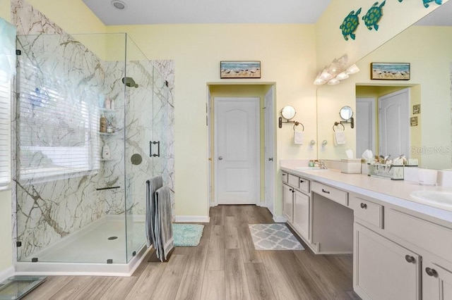 full bath with wood finished floors, a marble finish shower, and double vanity