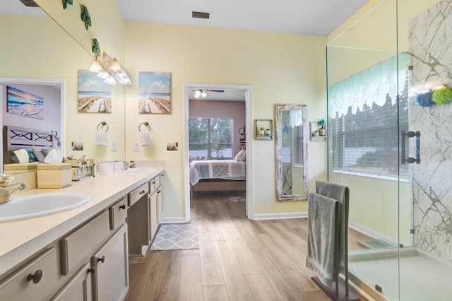 ensuite bathroom featuring wood finished floors, a stall shower, double vanity, a ceiling fan, and baseboards