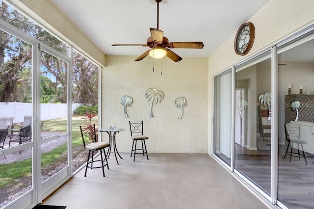 sunroom featuring a textured wall, a ceiling fan, and finished concrete flooring