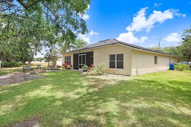 back of house featuring a lawn, stucco siding, and a sunroom