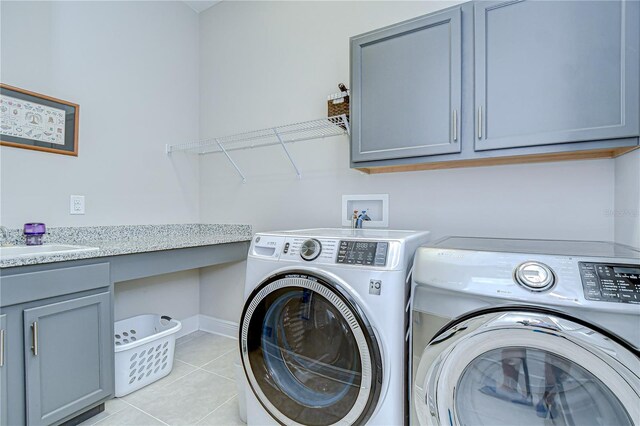 5728 Watercolor Dr, Lithia, FL 33547 - laundry room featuring separate washer and dryer, cabinet space, light tile patterned floors, and baseboards