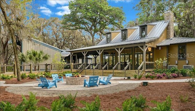 5728 Watercolor Dr, Lithia, FL 33547 - rear view of house with an outdoor fire pit, a chimney, metal roof, a patio area, and central AC