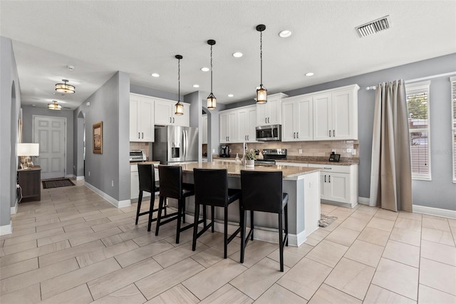 1436 30th Ave N, Saint Petersburg, FL 33704 - kitchen featuring appliances with stainless steel finishes, backsplash, a kitchen bar, recessed lighting, and an island with sink