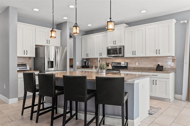 1436 30th Ave N, Saint Petersburg, FL 33704 - kitchen with appliances with stainless steel finishes, decorative backsplash, a kitchen bar, an island with sink, and white cabinets