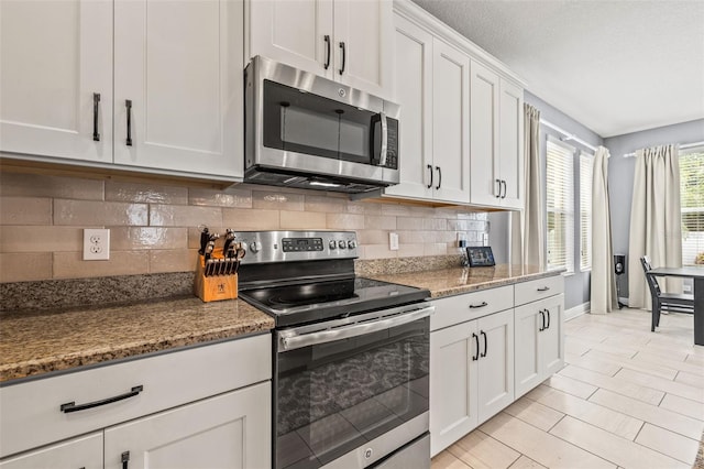 1436 30th Ave N, Saint Petersburg, FL 33704 - kitchen with appliances with stainless steel finishes, baseboards, backsplash, white cabinetry, and light stone counters
