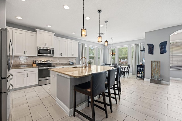 1436 30th Ave N, Saint Petersburg, FL 33704 - kitchen featuring appliances with stainless steel finishes, a sink, white cabinetry, light stone counters, and recessed lighting