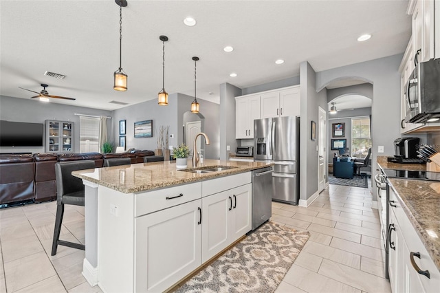 1436 30th Ave N, Saint Petersburg, FL 33704 - kitchen with stainless steel appliances, ceiling fan, a sink, arched walkways, and light stone counters