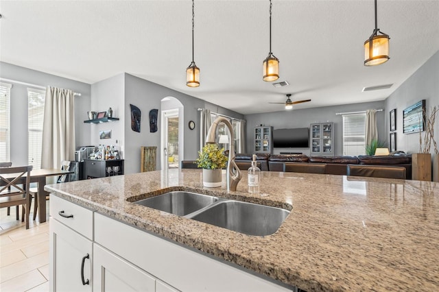 1436 30th Ave N, Saint Petersburg, FL 33704 - kitchen with a sink, arched walkways, decorative light fixtures, light stone counters, and a textured ceiling