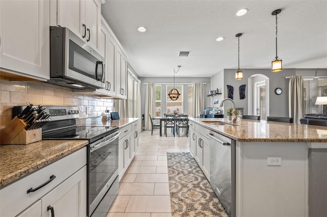 1436 30th Ave N, Saint Petersburg, FL 33704 - kitchen with stainless steel appliances, a sink, tasteful backsplash, a center island with sink, and arched walkways
