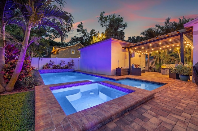 1436 30th Ave N, Saint Petersburg, FL 33704 - pool at dusk featuring an in-ground hot tub, a patio, and a fenced backyard