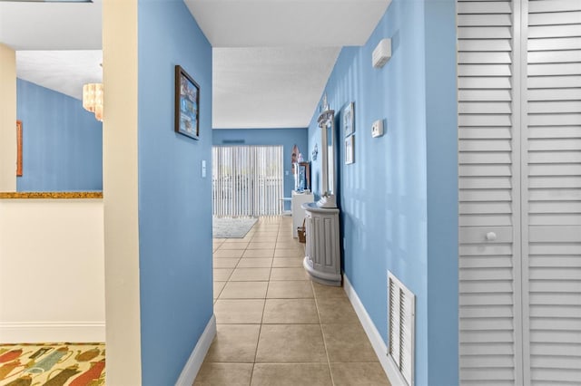 4900 Brittany Dr S Unit 209, Saint Petersburg, FL 33715 - corridor featuring baseboards, tile patterned flooring, and a chandelier