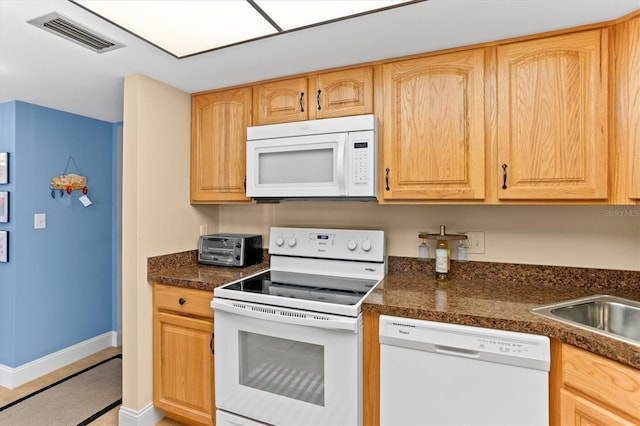 4900 Brittany Dr S Unit 209, Saint Petersburg, FL 33715 - kitchen with white appliances, dark countertops, baseboards, and light brown cabinetry