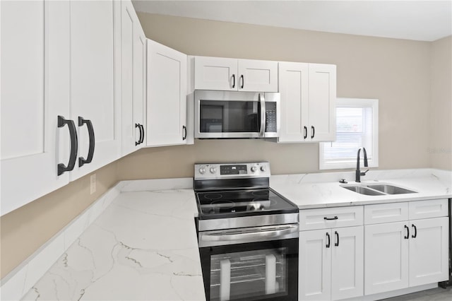 1101 Dr Martin L King Jr Way, Haines City, FL 33844 - kitchen with stainless steel appliances, a sink, white cabinets, and light stone countertops