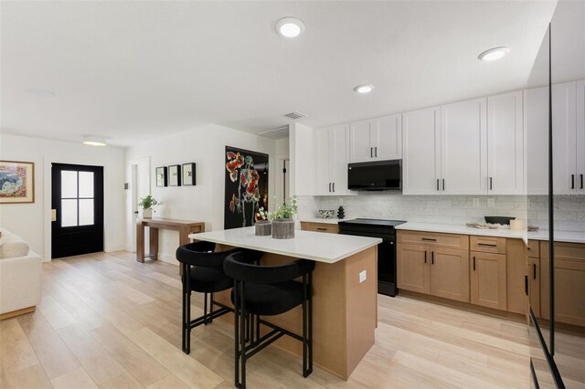 4618 Bayshore Blvd NE, Saint Petersburg, FL 33703 - kitchen with black appliances, a kitchen bar, light countertops, decorative backsplash, and recessed lighting