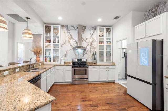 kitchen with stainless steel appliances, wall chimney exhaust hood, light stone counters, a sink, and recessed lighting