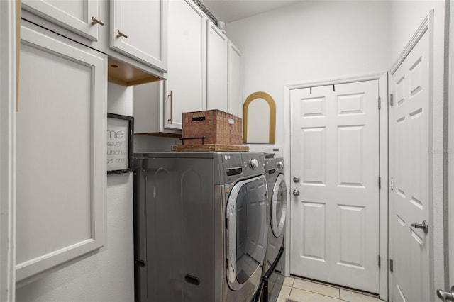 clothes washing area featuring independent washer and dryer, cabinet space, and light tile patterned floors